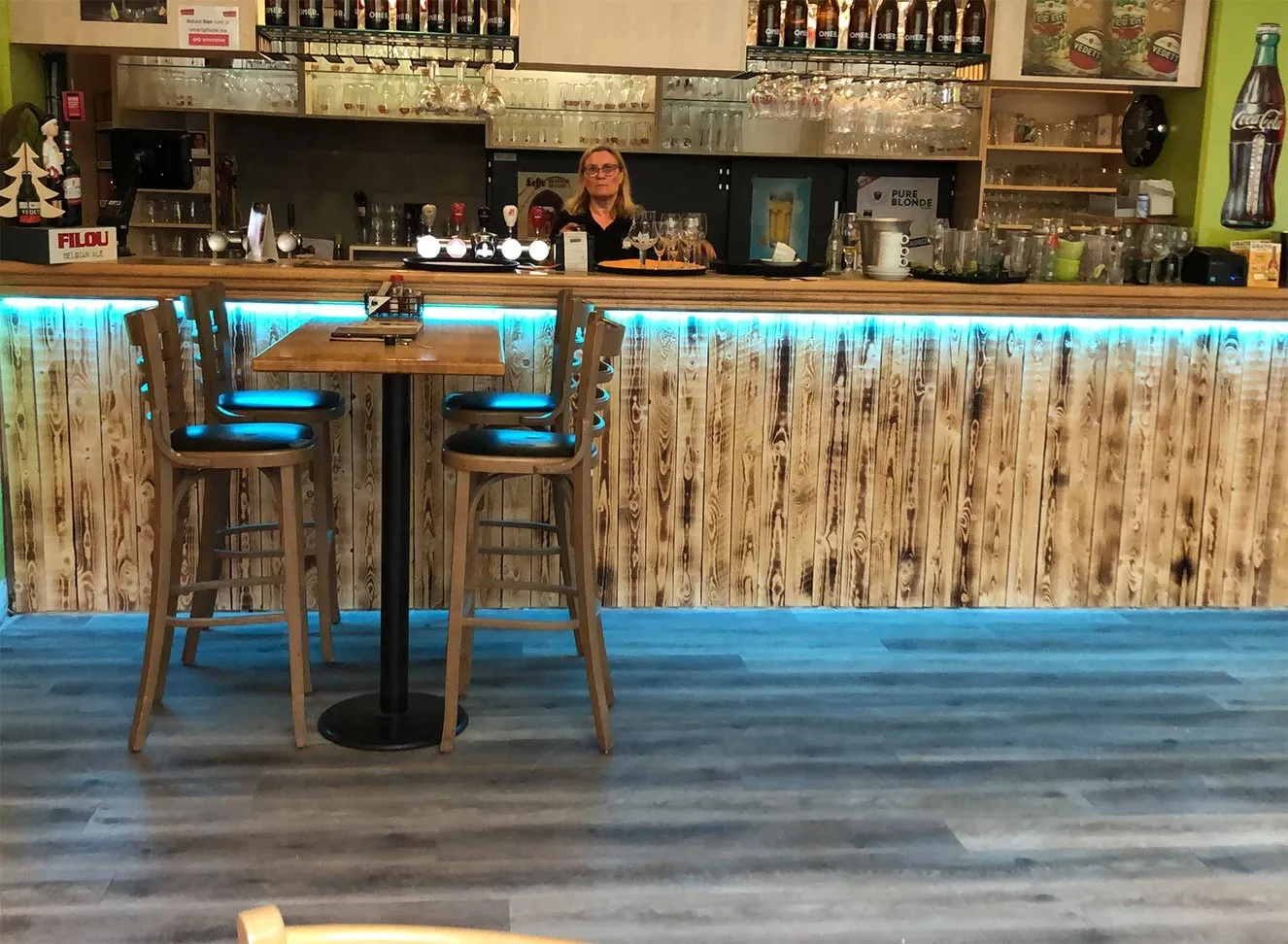 De bar met hoge krukken en blauw licht onder de toog