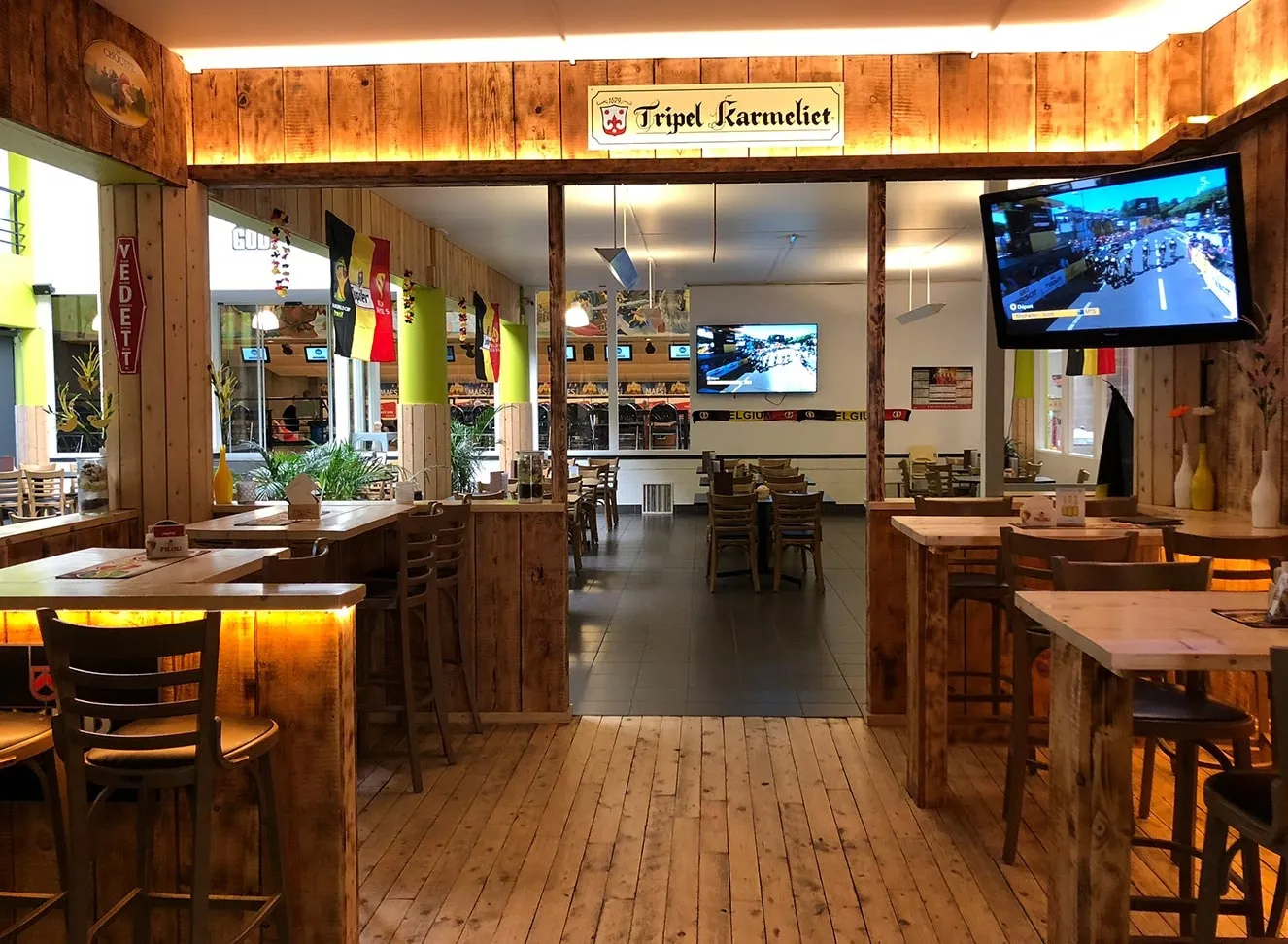Het eetcafé met houten tafels, een lange toog en televisieschermen