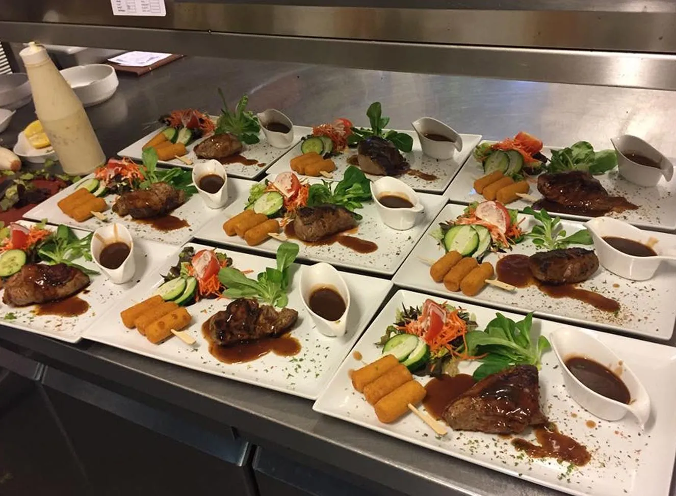 Borden met steak, saus en groenten, klaar om op te dienen voor een groep