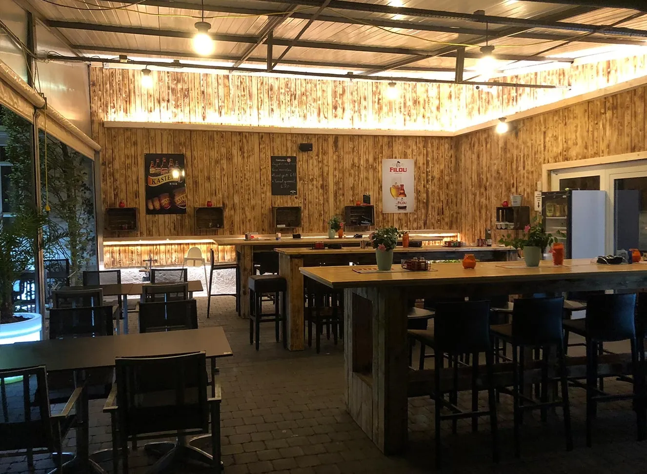 Het overdekte terras ’s avonds, met de lampen aan